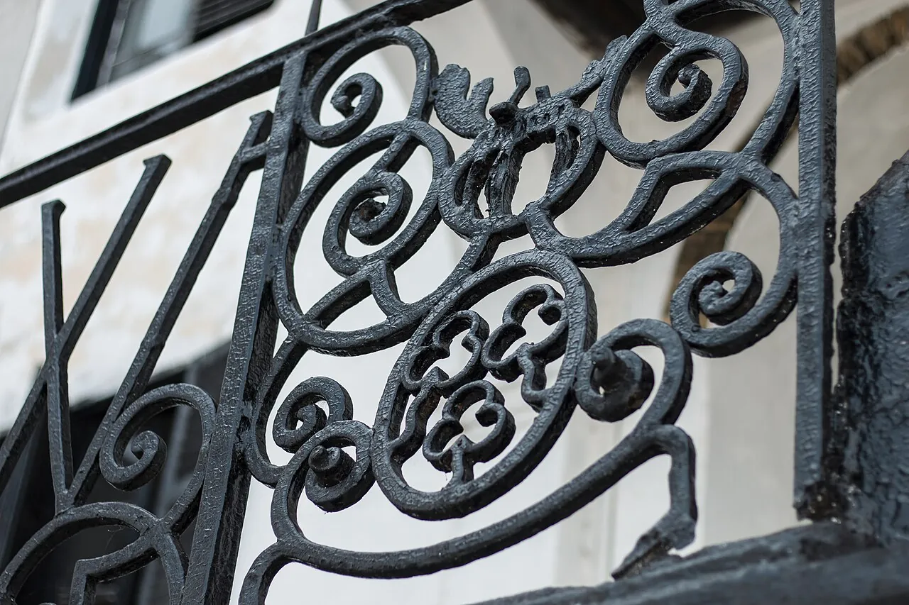 Black wrought-iron railing panels filled with interlocking C- and S-shaped scrolls.