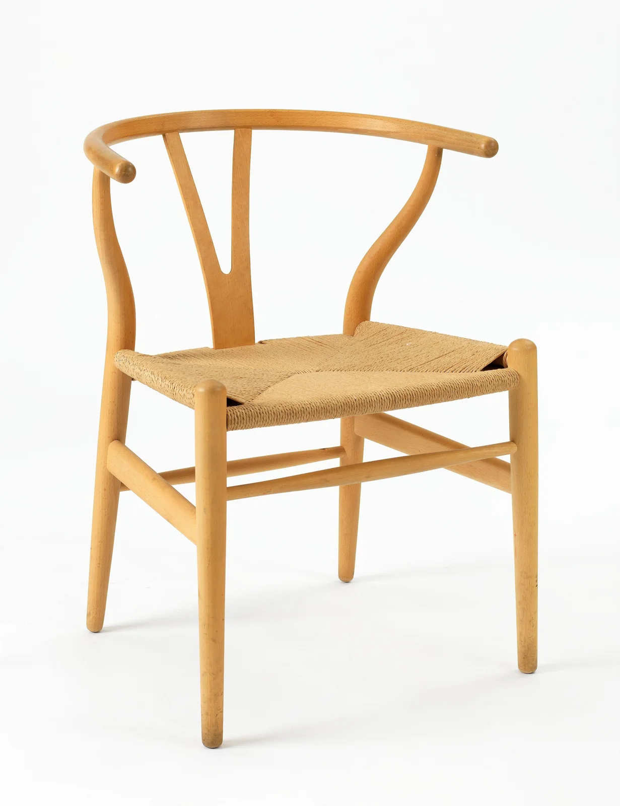 Hans Wegner CH24 Wishbone chair in beech, with a continuous curved back and arm rail, a centered Y-shaped support, tapered frame members, and a woven seat