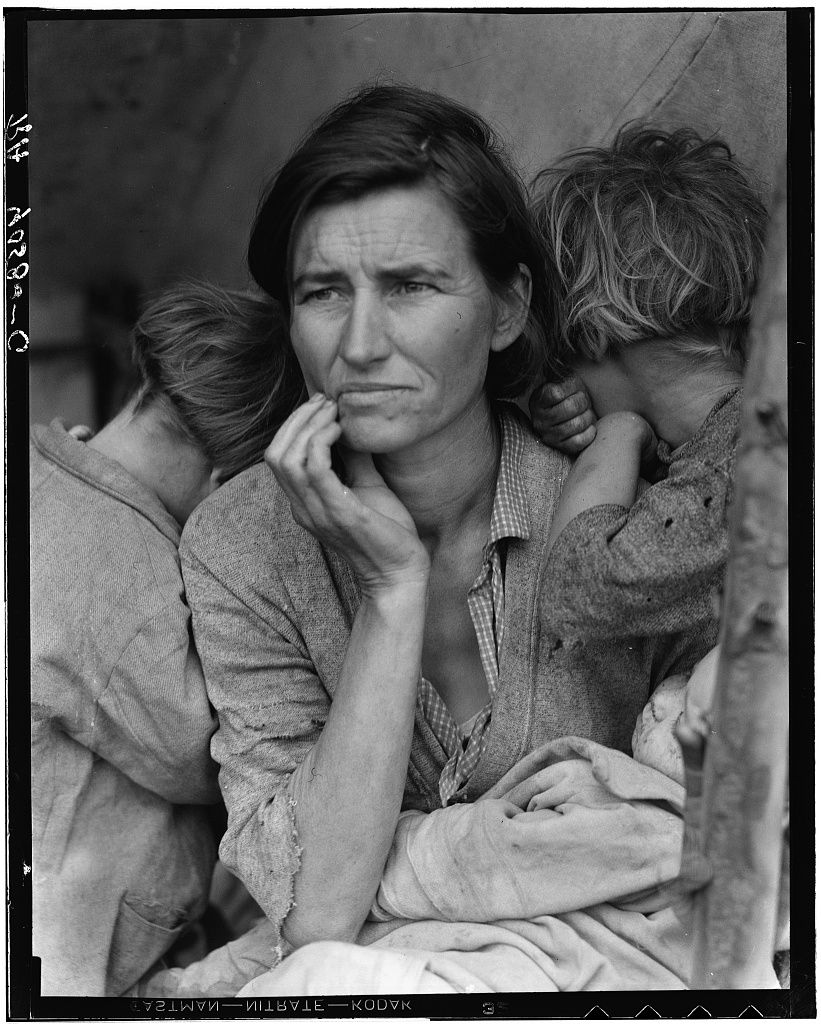 Florence Thompson sits with her hand at her face as two children turn away against her shoulders and an infant rests in her lap