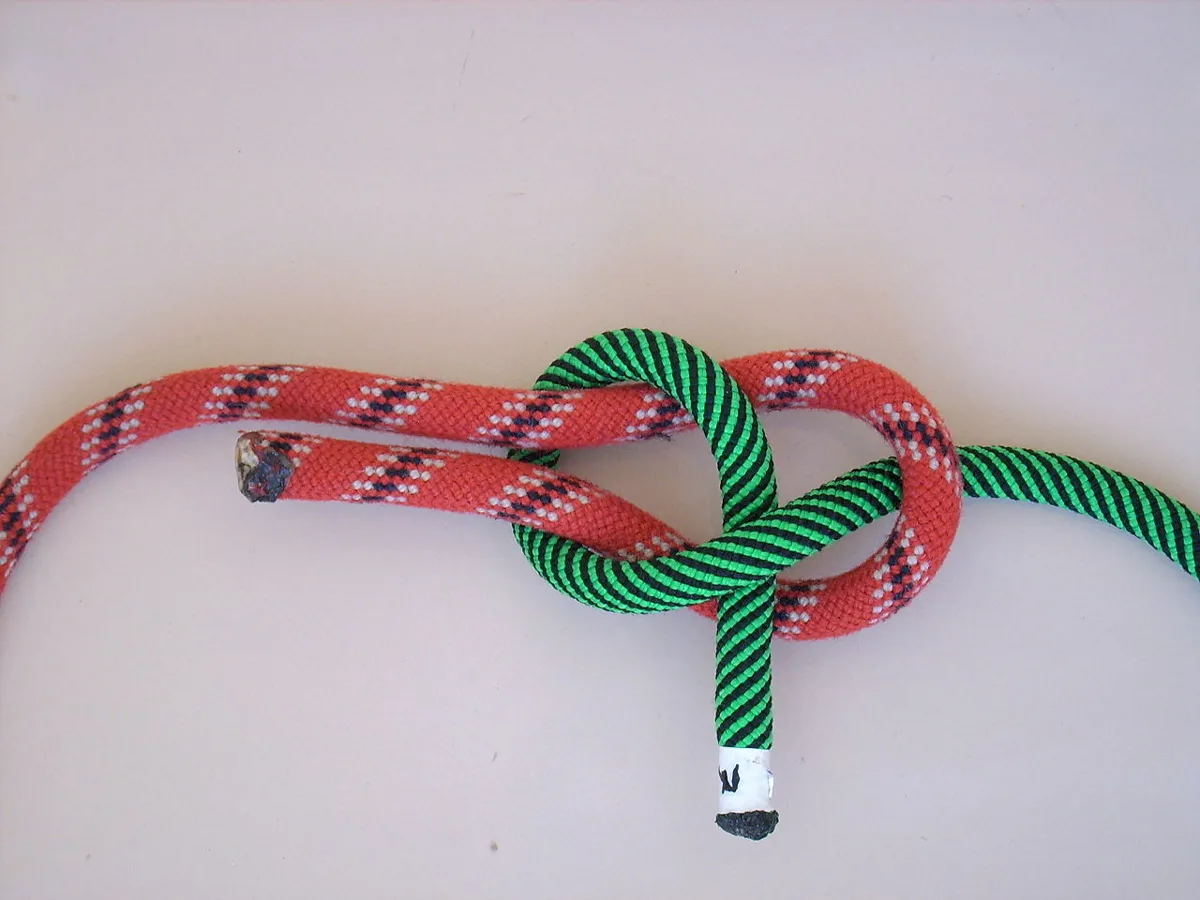 A thick red rope folded into a bight with a thinner green rope passed up through it, around both legs, and tucked under itself.